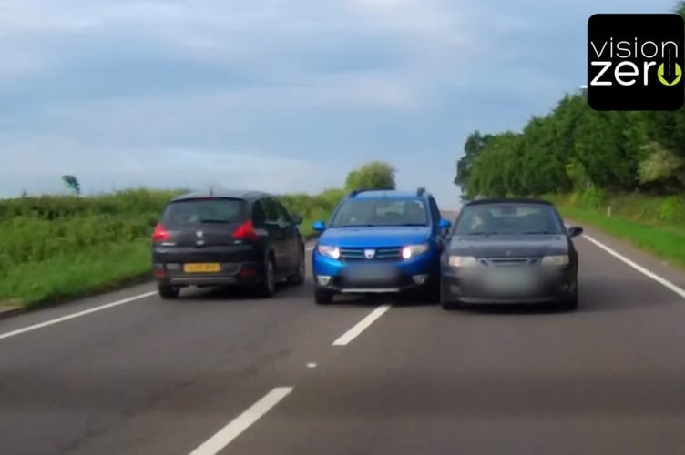 A car overtaking another dangerously, with inches to spare, while vehicles pass in the opposite direction