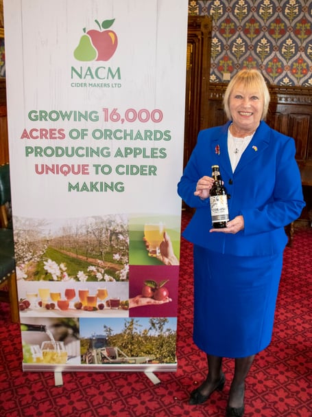Sheryll at the NACM banner with a bottle of Cornish Orchards