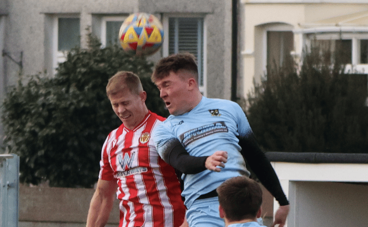 Saltash United’s Ed Goodman (left) in aerial combat against Buckland Athletic.