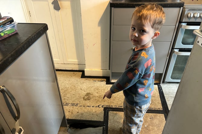 Logan Jones, four, points to the hole that has appeared in the kitchen of the family\'s council house near Looe