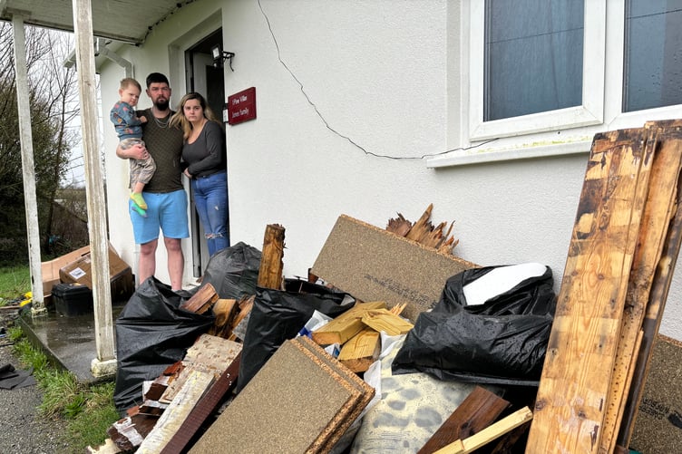 Dean and Natalie Jones with their son Logan outside their home with the rotten flooring which has been removed from their council house in Lanreath