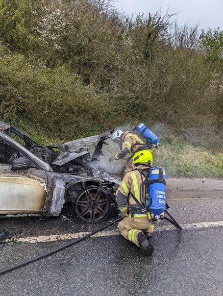 The wreckage of the car being extinguished by officers