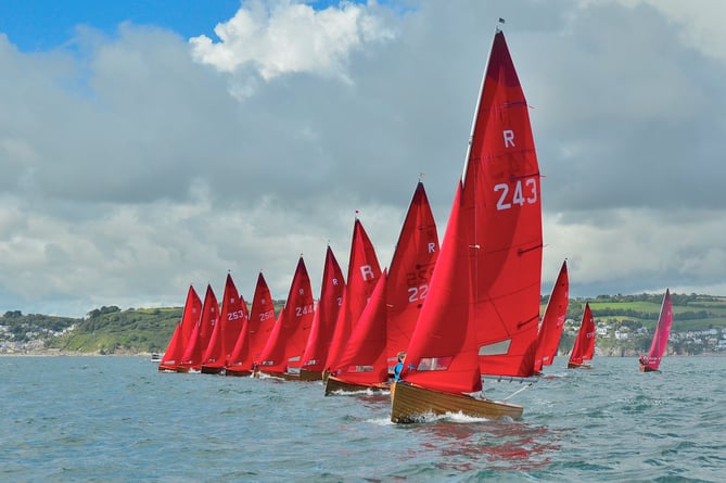 Charge of the Red Brigade: Looe’s distinctive Redwing fleet – the class was specifically designed for Looe Bay by the legendary Uffa Fox in 1938 – races across the starting line at one of the twice weekly events held during the summer months. (Picture: Neil Richardson)