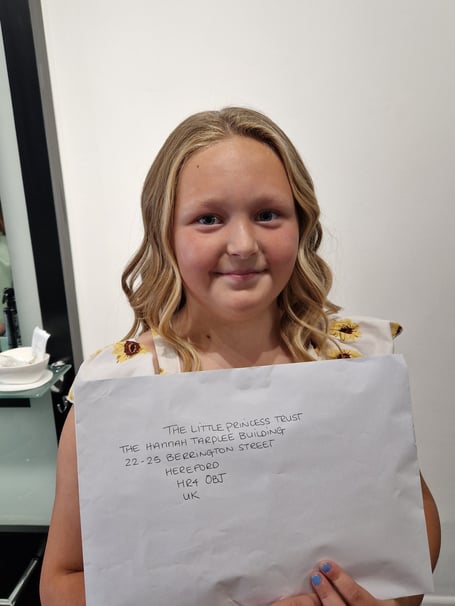 Taylor-May holding her generous hair donation to the Little Princess Trust.