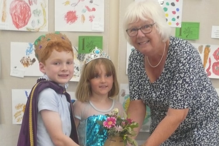 Rev Marilyn Elliott who opened the Linkinhorne Horticultural  Show at the Parish Hall in Upton Cross, being presented with a floral gift from Rilla Mill Carnival King, Harry Davy and Carnival Queen, Merryn Davy