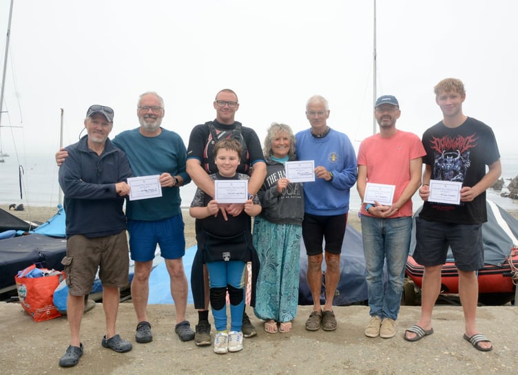 The winners of certificates presented after the races.
From left: Third overall Phill Holmes and Andrew Molloy who sailed Andrew’s 2000, club commodore Mark Lentell who presented the certificates, with son Will in front, (who gained his certificate for completing his first Cawsand Bay Sailing Club regatta), Penny Knowles and Ian Turpitt who were second overall in Ian’s 2000 and winner Guy Pearson who won in his Laser Radial. Finlay Morgan, far right, won the standard Laser class.