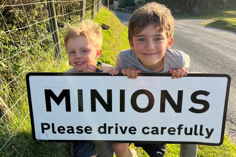 Nicholas Brodie and his big brother Jake crouching by the road sign in the village of Minions
