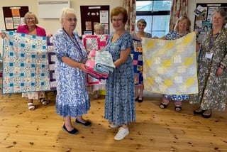Members of Wilcove WI present quilts to representatives from Project Linus