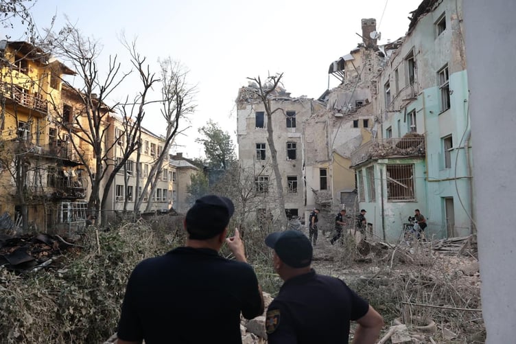 Members of Ukraine's emergency services survey damage to buildings in Lviv after a recent air strike. The city is just 30 miles from the border with Poland