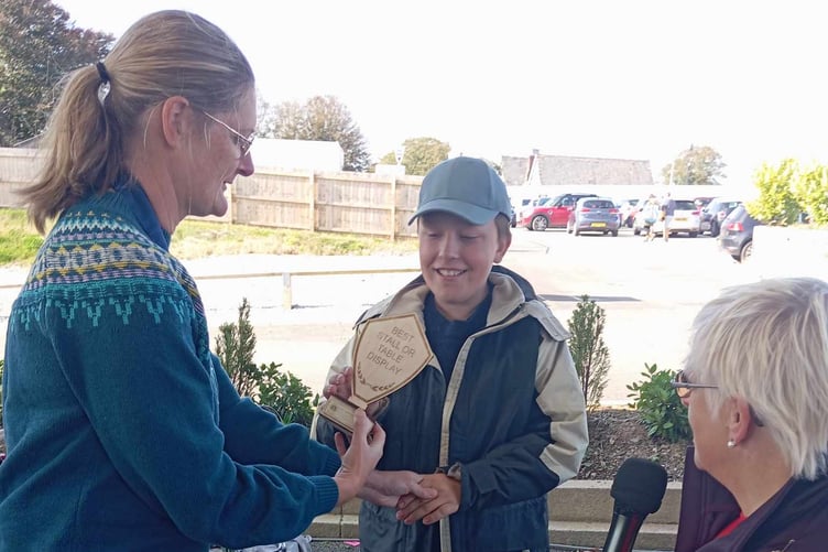 LIONS president Lisa Ince and mayor Christina Whitty present Harry with a trophy for the best table display at St Matthew's fair. The youngster has a stall with items he creates from horseshoes