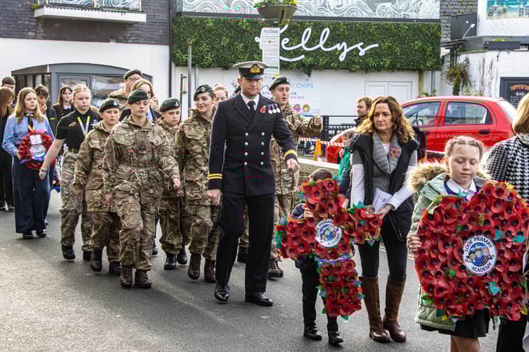 Looe Primary Academy children walk in the procession to the war memorial to lay a large poppy and cross to remember Looe's fallen. (Picture: RNLI/ Ian Foster)