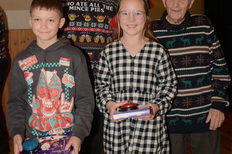 Ben and Eva pictured after switching on the Christmas lights, together with hall chairman Stephen Michael (right), and Jon Kidd (left) Chairman of Rame Peninsula Male Voice Choir and local Councillor. (Picture: Sue Clemens)