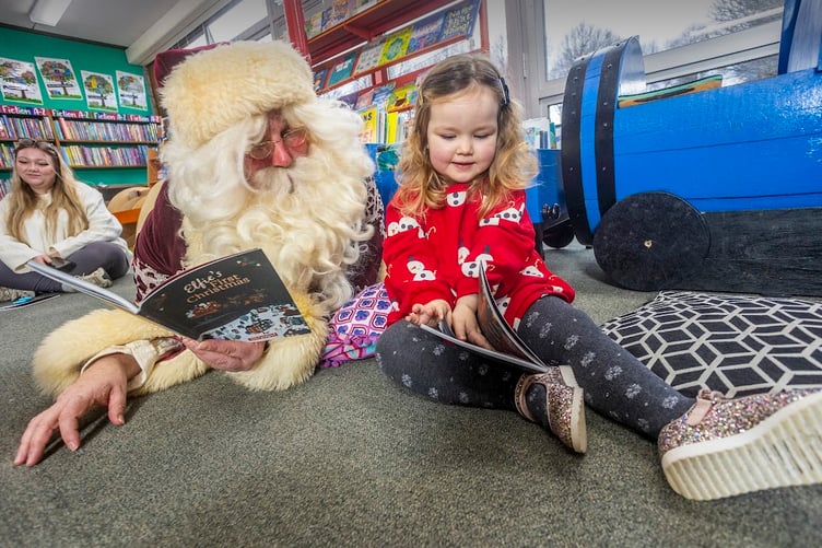 Santa reading a festive story with a youngster.