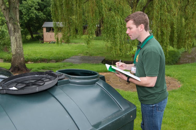 An OFTEC technician inspects an oil tank as part of a routine service