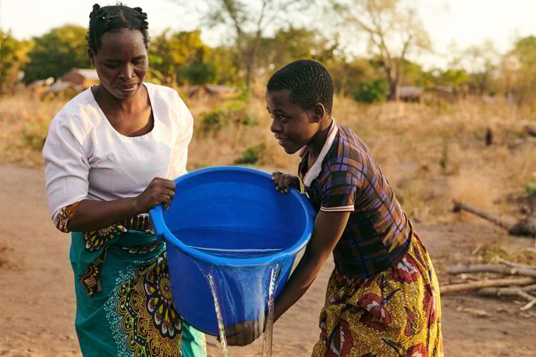 Sileni, 33, and her daughter, Merifa, 15, washing clothes with clean water, M’doko, Malawi. June 2024.