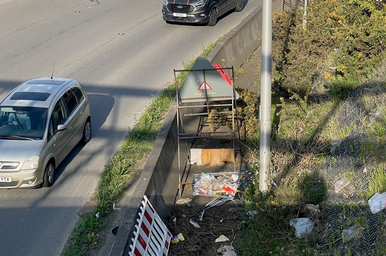 An abandoned shopping trolley filled with litter alongside the Carkeel Roundabout