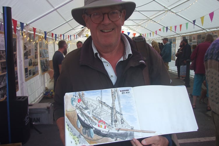 Artist Adrian Bishop shows off one of his paintings at this year's Looe Lugger Classics event. (Picture: Peter Kinver)