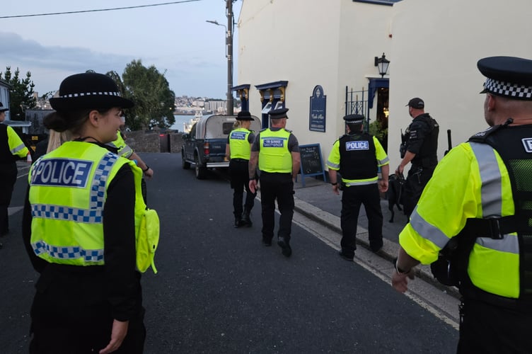 A team of police officers, tri service officers, student officers and special constables prepare to enter a pub in Torpoint alongside a passive drugs dog and handler as part of Operation PAD