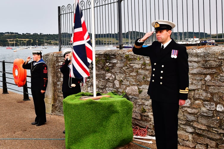 Service personnel salute as the Union Jack is raised as part of the VJ Day celebrations in Torpoint