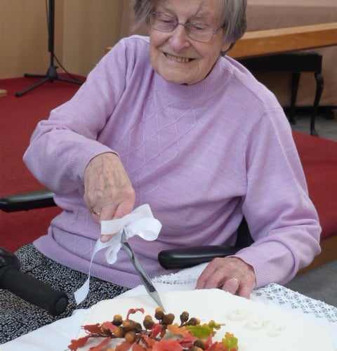 Lena Richards cutting the celebration cake which had been made by Kathryn Bunkum