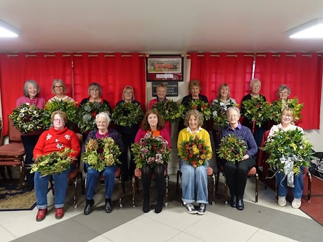 Members of Liskeard Flower Club proudly displaying their completed Christmas wreaths