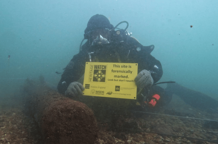 A diver holding an underwater sign indicating that a site has been forensically marked. This means visiting divers can look but not touch. (Picture: MSDS Marine)