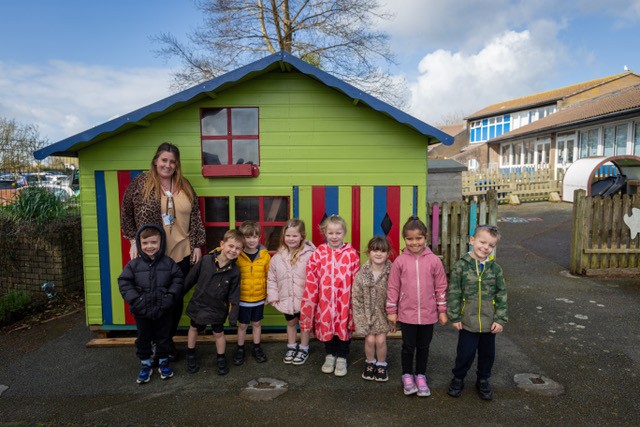 Staff and pupils at Looe Primary Academy pictured outside of their newly refurbished playhouse