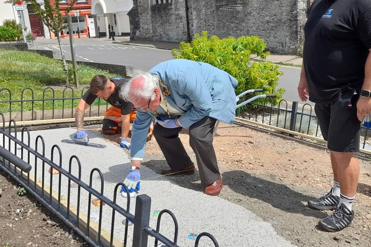 Saltash Mayor, Cllr Brian Stoyel, helps to reinstate one of the pebbles in the WWI Pebble Memorial in the Peace Garden at Alexandra Square